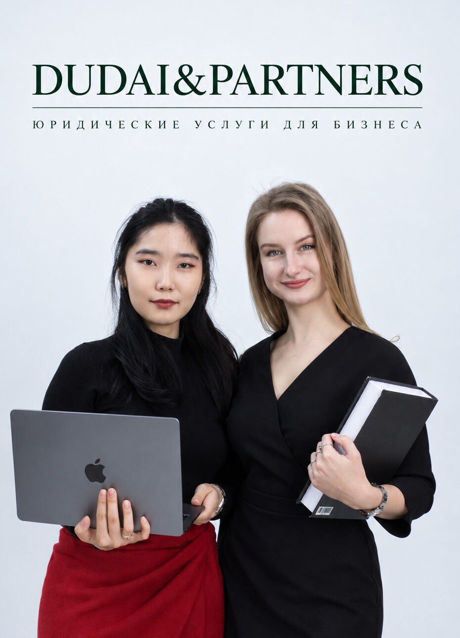 Two business professionals, a woman of Asian descent and a blonde woman, stand together holding a laptop and a notebook in front of a white backdrop with DUDAI&PARTNERS branding and Russian text beneath it.